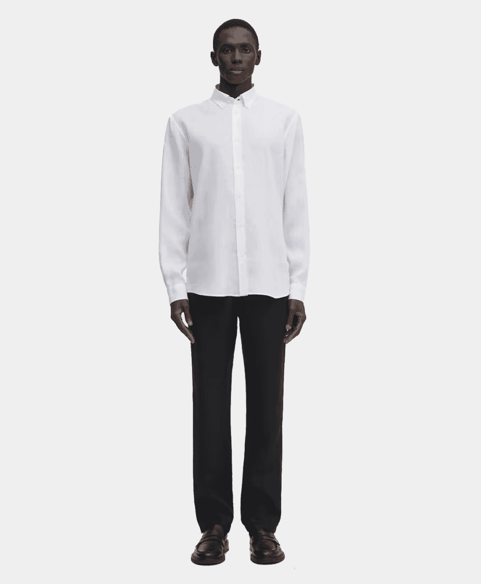 Man in a crisp white linen shirt and black trousers for a minimalist formal-casual appearance.