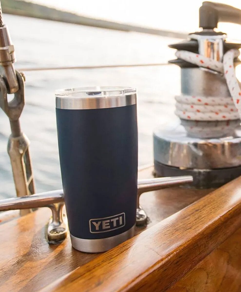 Navy blue YETI insulated tumbler sitting on a wooden boat deck.