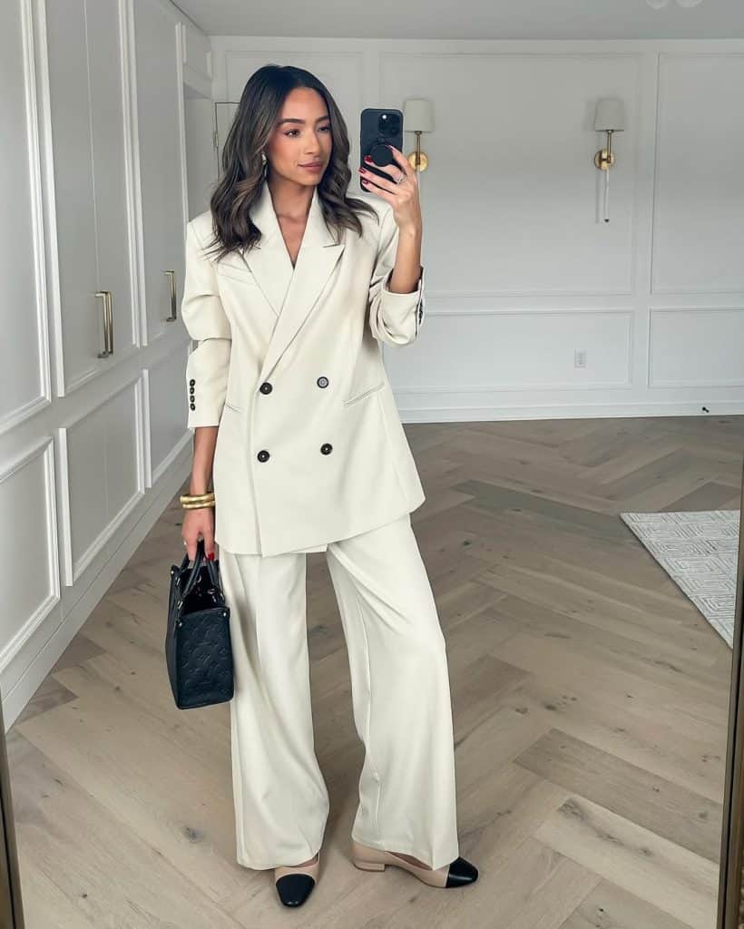 A mirror selfie showing a woman in a full cream-colored double-breasted suit with wide-leg trousers.