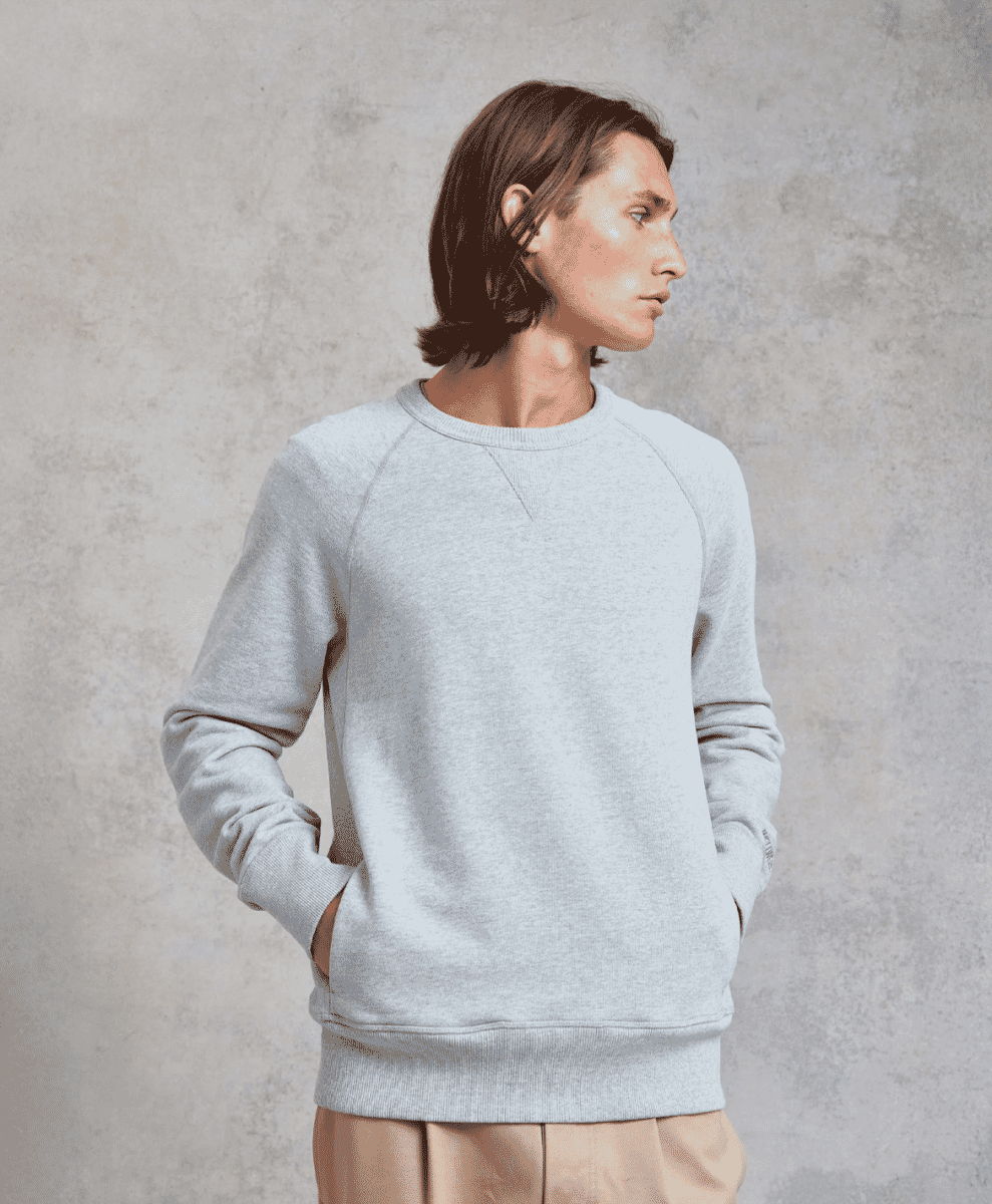 Male model in a light gray heathered crewneck sweatshirt with raglan sleeves.