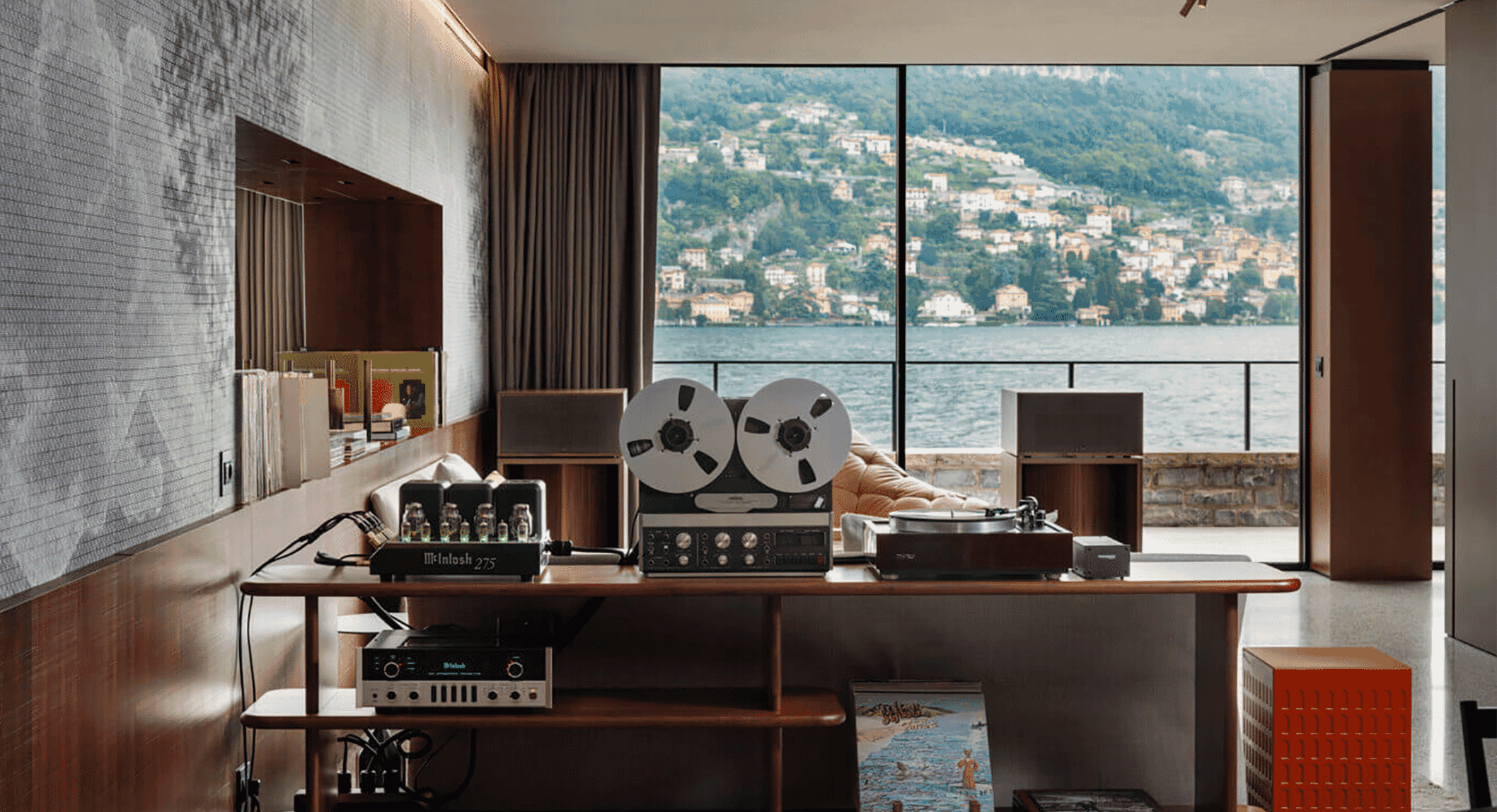 A minimalist wooden desk in the Darsena Suite featuring high-fidelity vintage audio components against a backdrop of Lake Como.