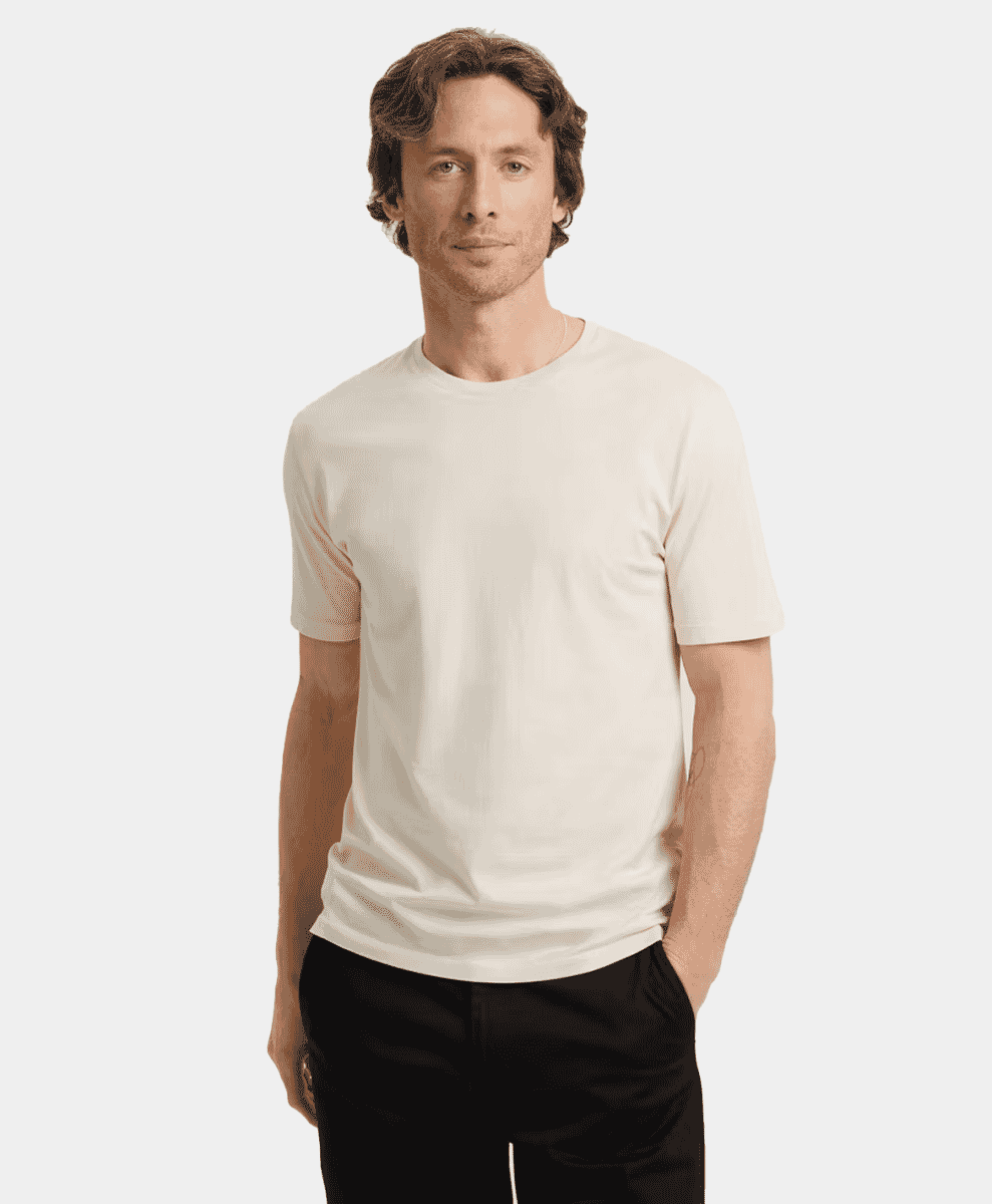 A man in a minimalist off-white short-sleeve t-shirt against a neutral background.