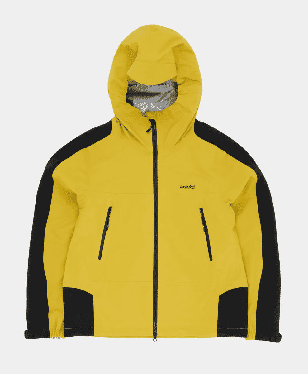 A vibrant yellow Gramicci 3L Guide Jacket with black waterproof paneling and a hood.