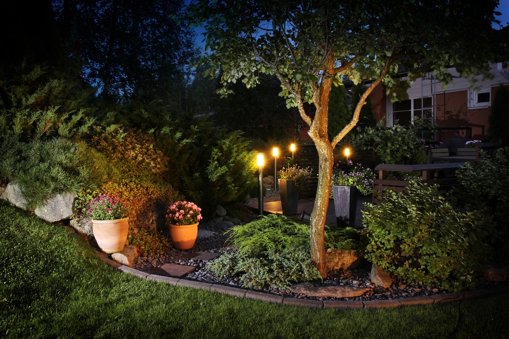 A peaceful garden at night with warm solar-powered pathway lights and stone borders.
