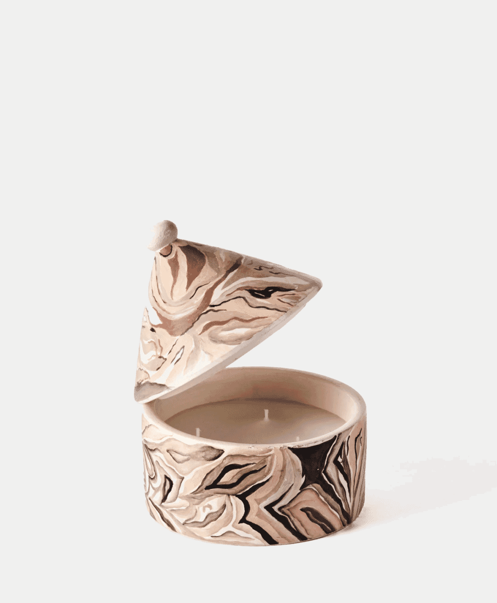 A marbled ceramic candle holder with three wicks and a matching lid.