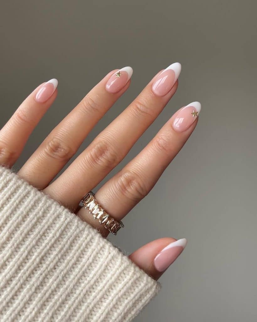 French manicure nails with small gold star accents paired with a cream sweater.