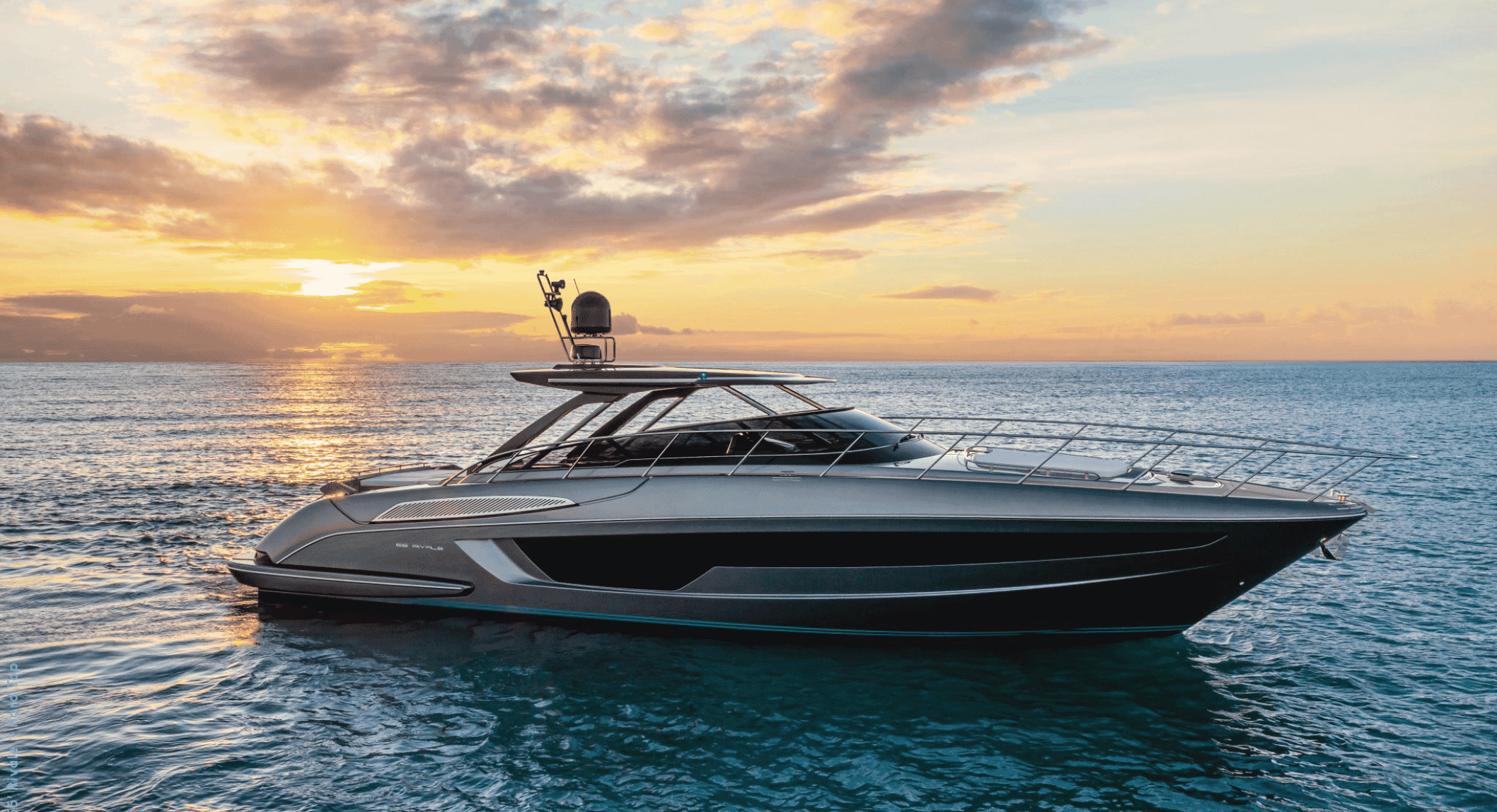 Sleek modern luxury yacht gliding across calm ocean waters under a golden sunset
