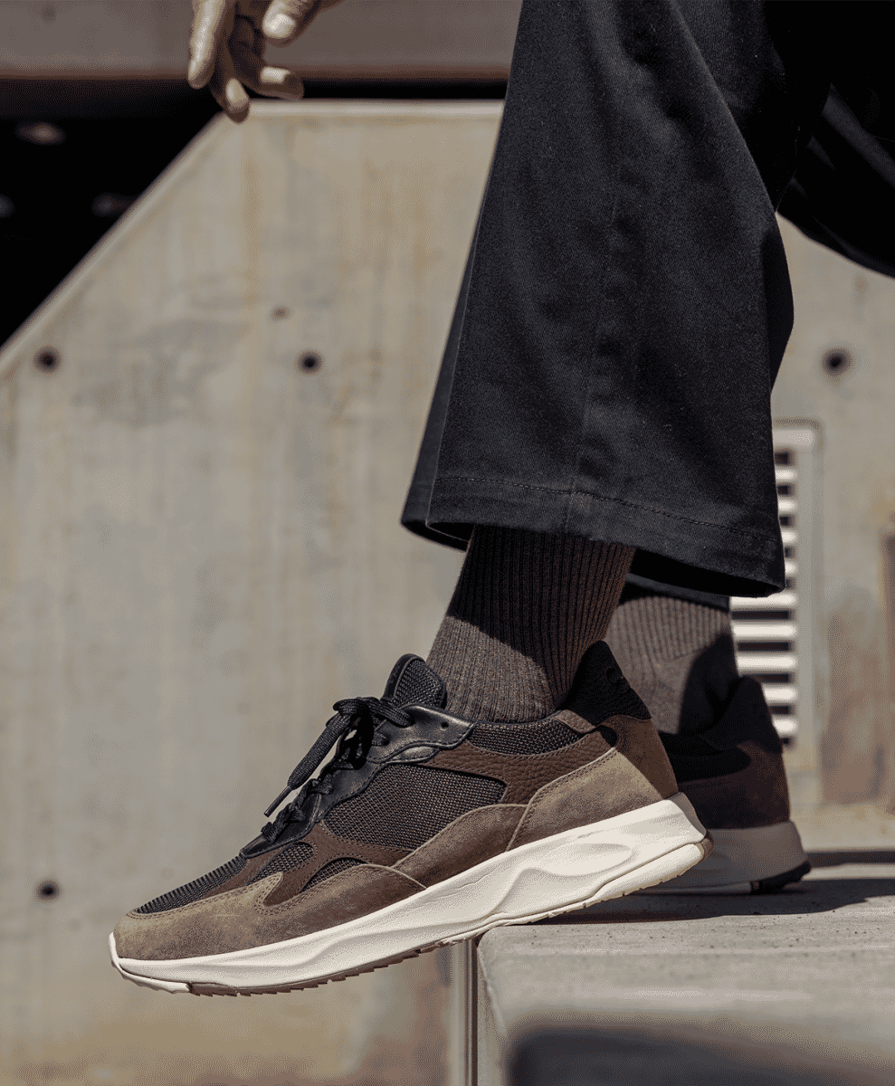 Brown and black suede Salazar sneakers on a concrete step with dark trousers.