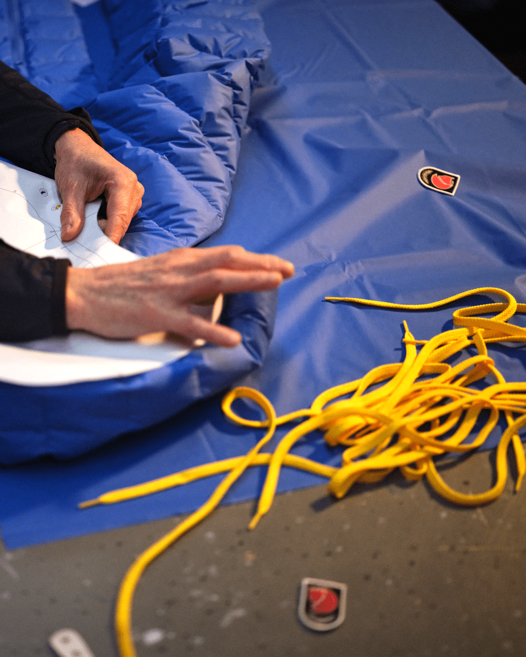 Close-up of a blue padded jacket being assembled in a professional garment workshop.