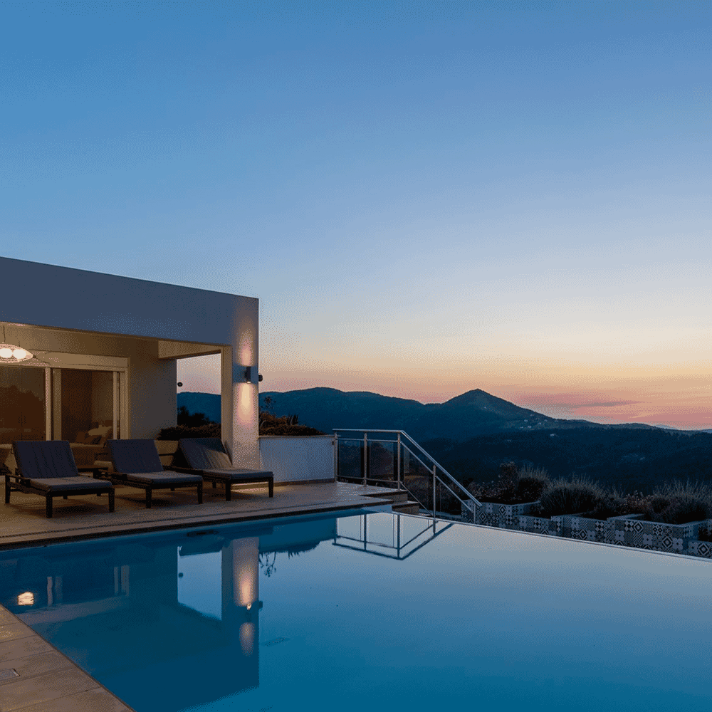 A serene infinity pool at twilight with a majestic mountain backdrop.
