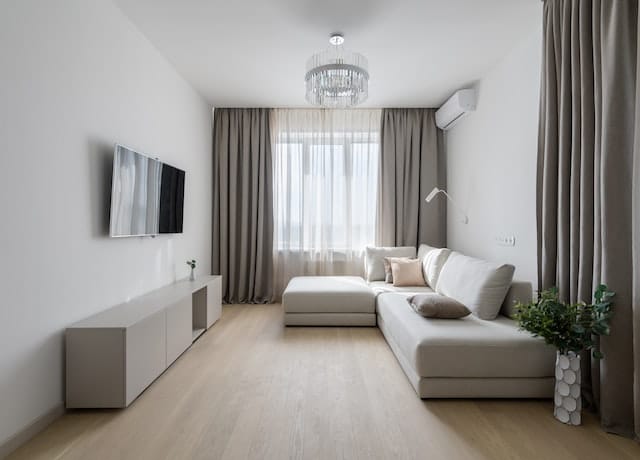 Modern living room with a white sectional sofa and floor-skimming neutral curtains.