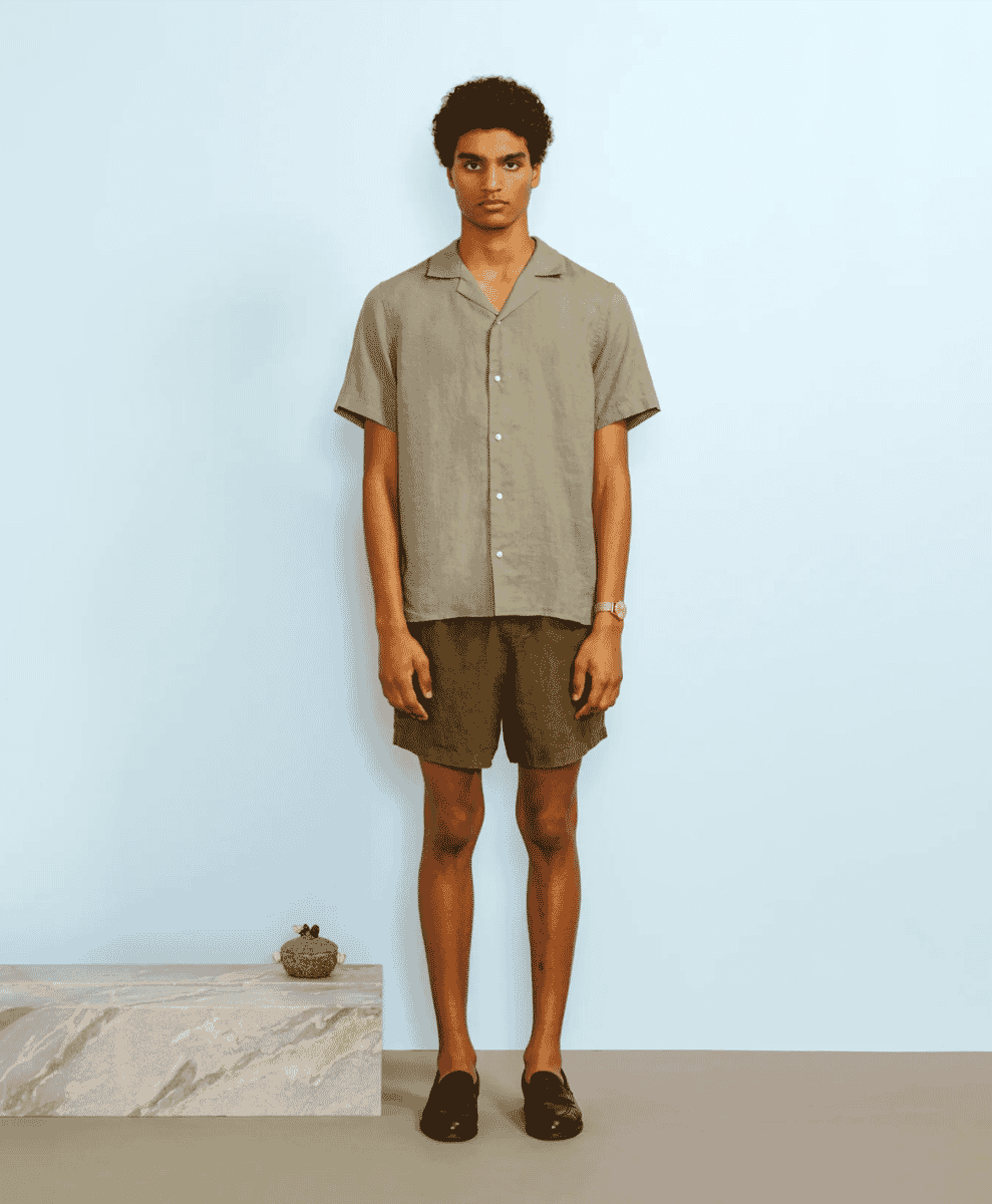 A man in a beige short-sleeved camp-collar shirt and black loafers