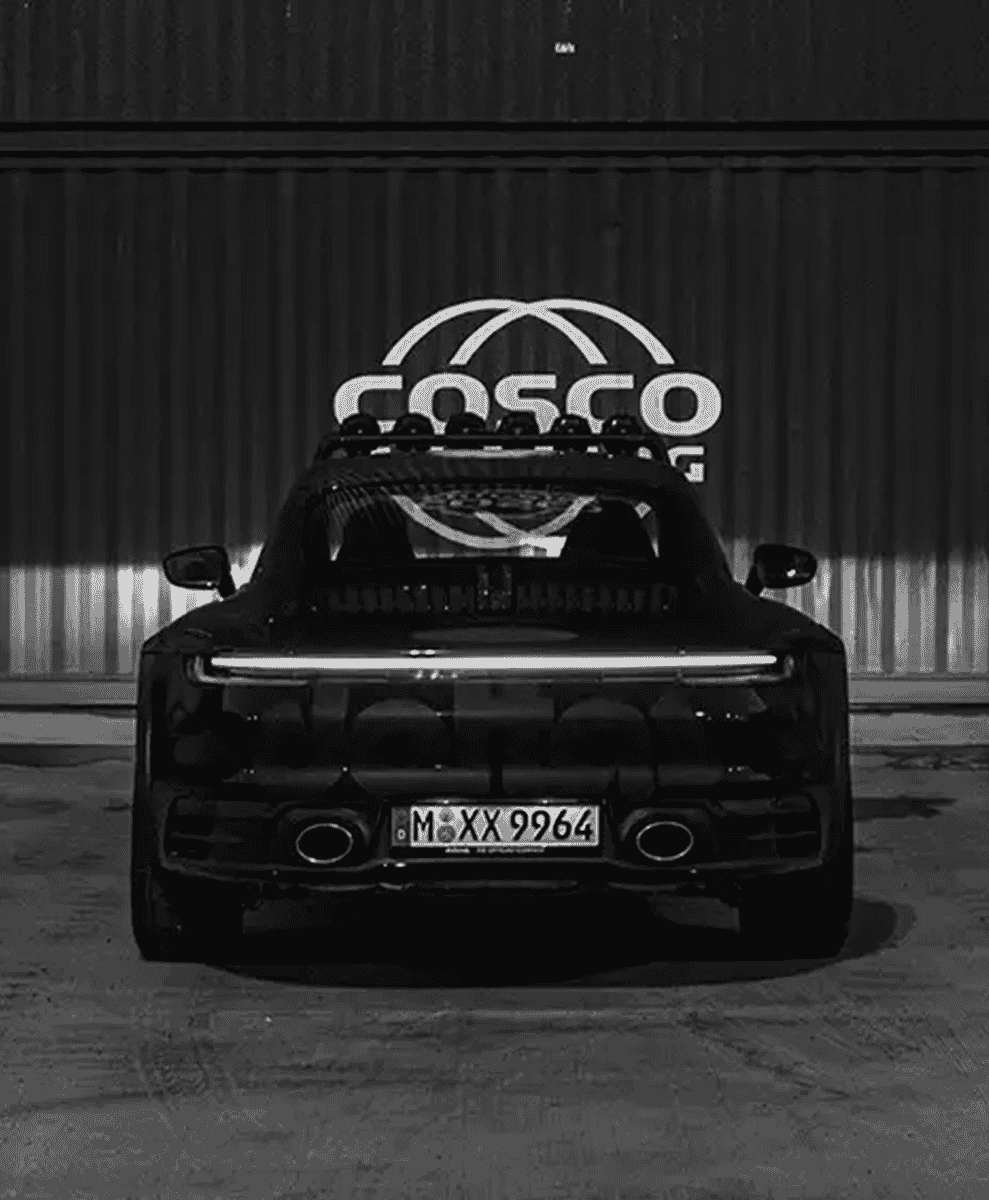 Black-and-white rear view of a modified sports car showing roof-mounted lighting equipment.