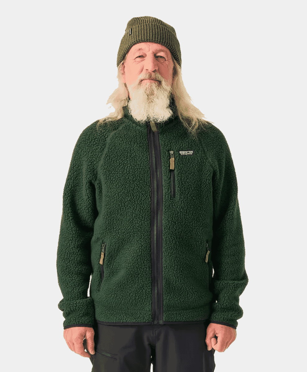 An elderly man with a white beard wearing a dark green fleece jacket and a beanie.