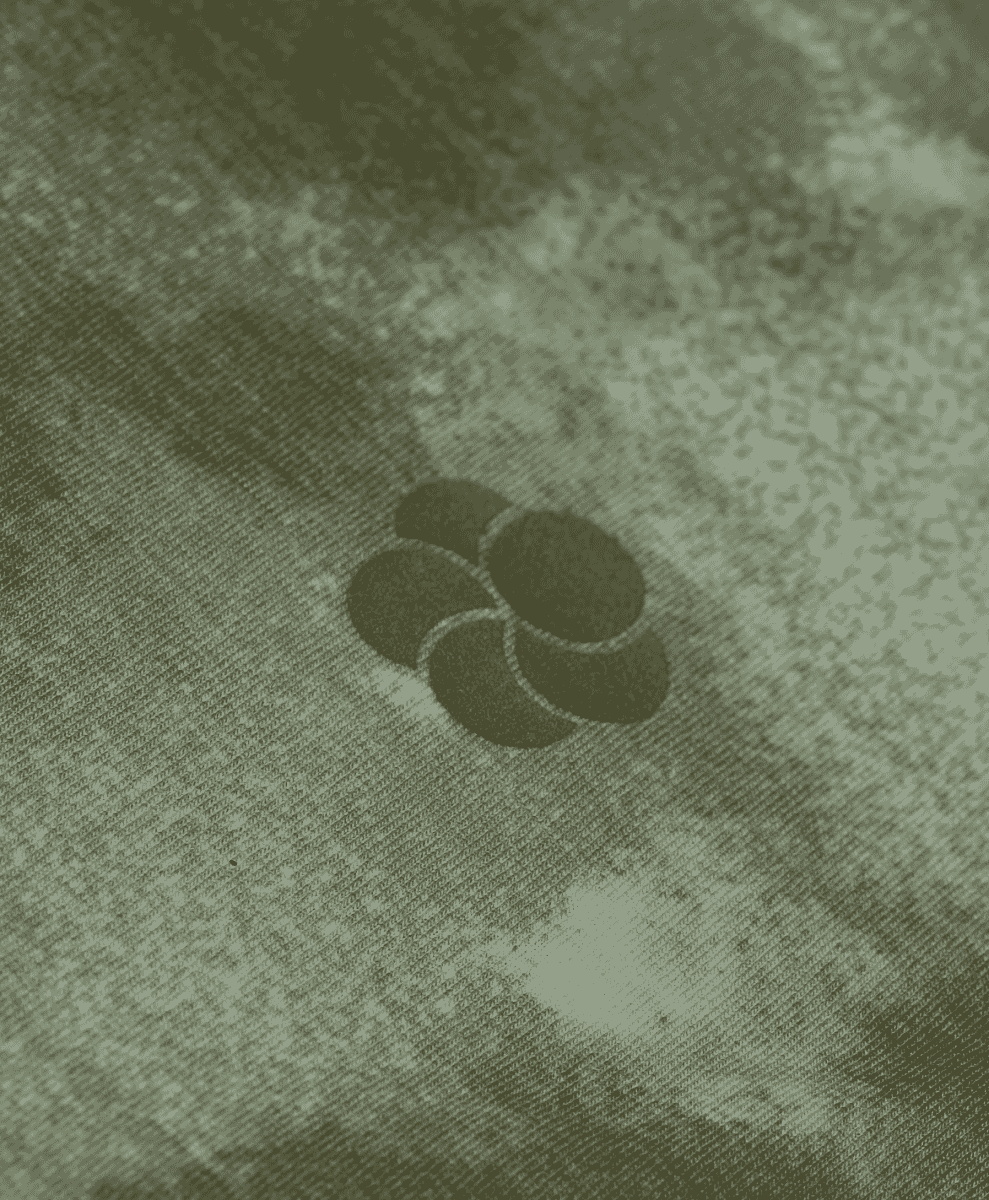 Close-up of textured green fabric with a dark floral embroidery.