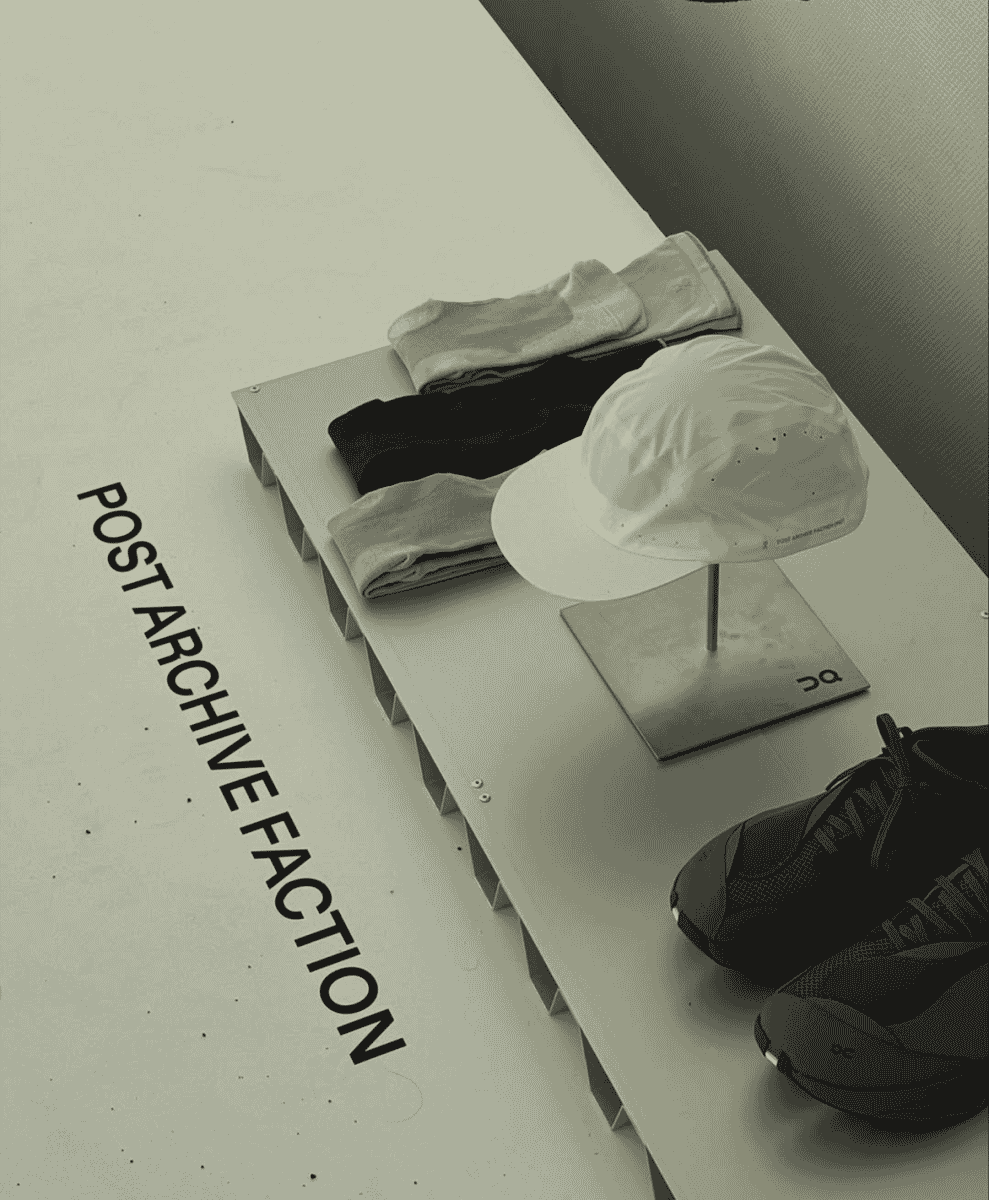 A display of monochrome athletic socks, a cap, and running shoes on a minimalist shelf.