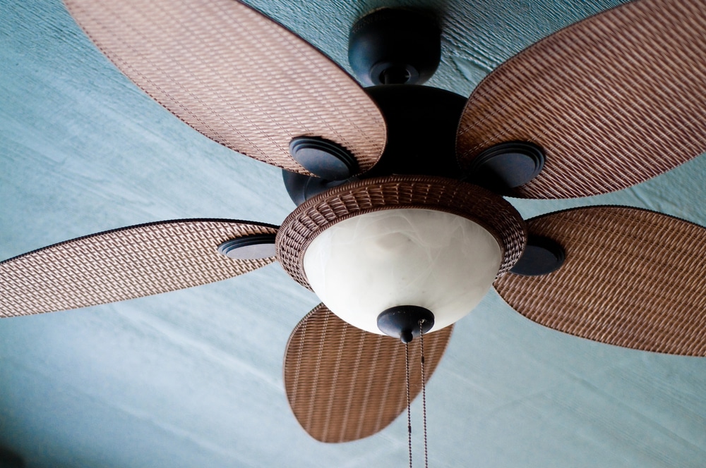 Close-up detail of a ceiling fan with intricate woven blades and a frosted glass light.