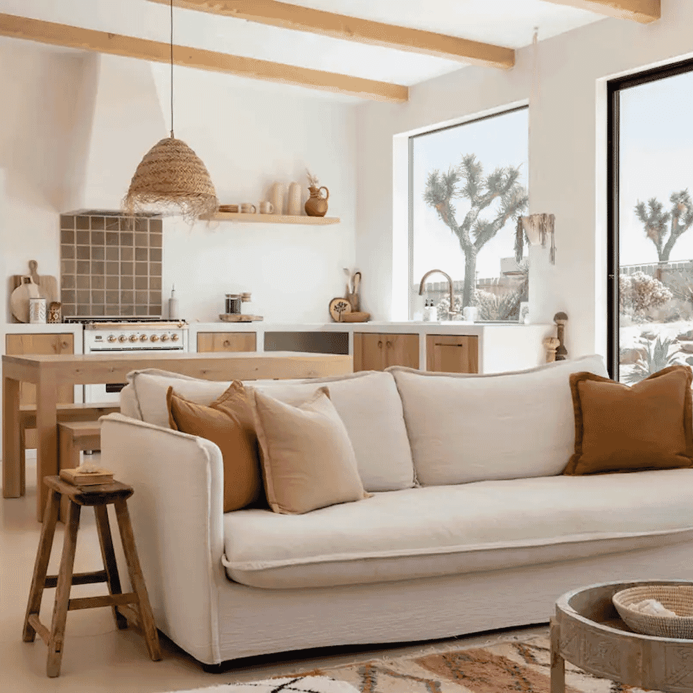 A cozy bohemian living room with earth-toned pillows, wooden beams, and a woven pendant light.