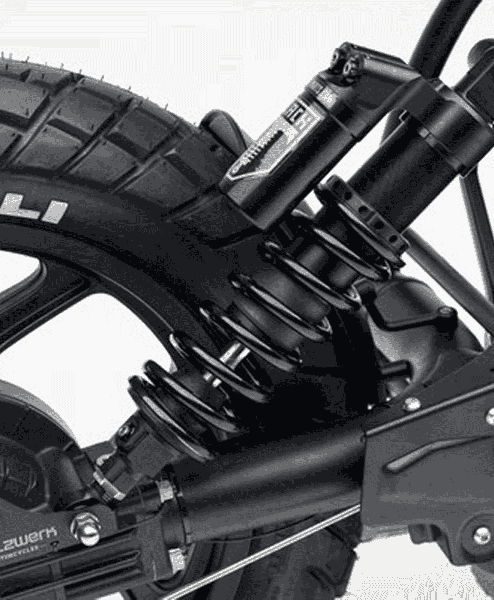 Black and white macro shot of a motorcycle rear suspension spring and a Pirelli tire with deep tread.