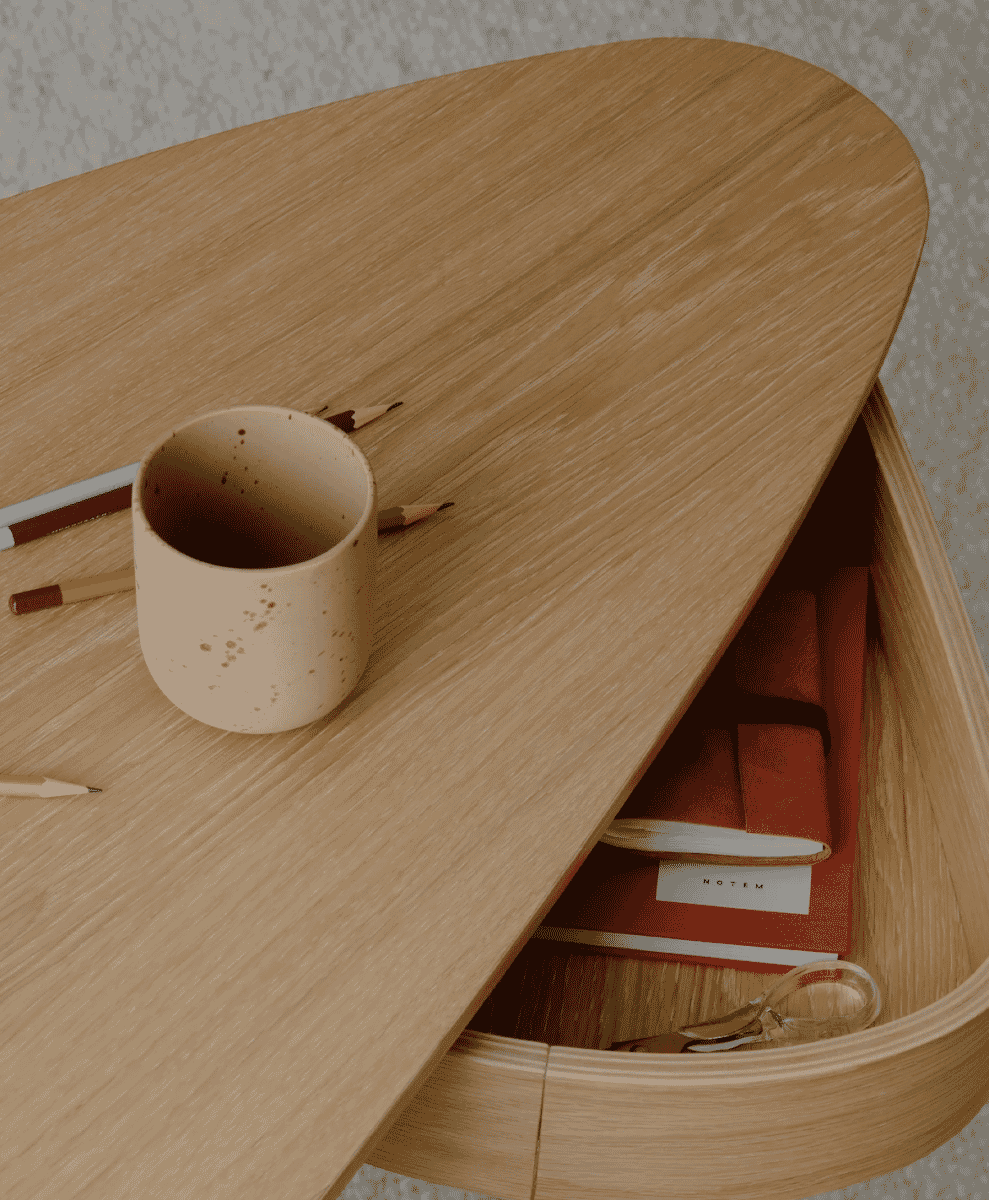 Top-down view of an oak desk surface styled with a ceramic mug, pencils, and notebooks.