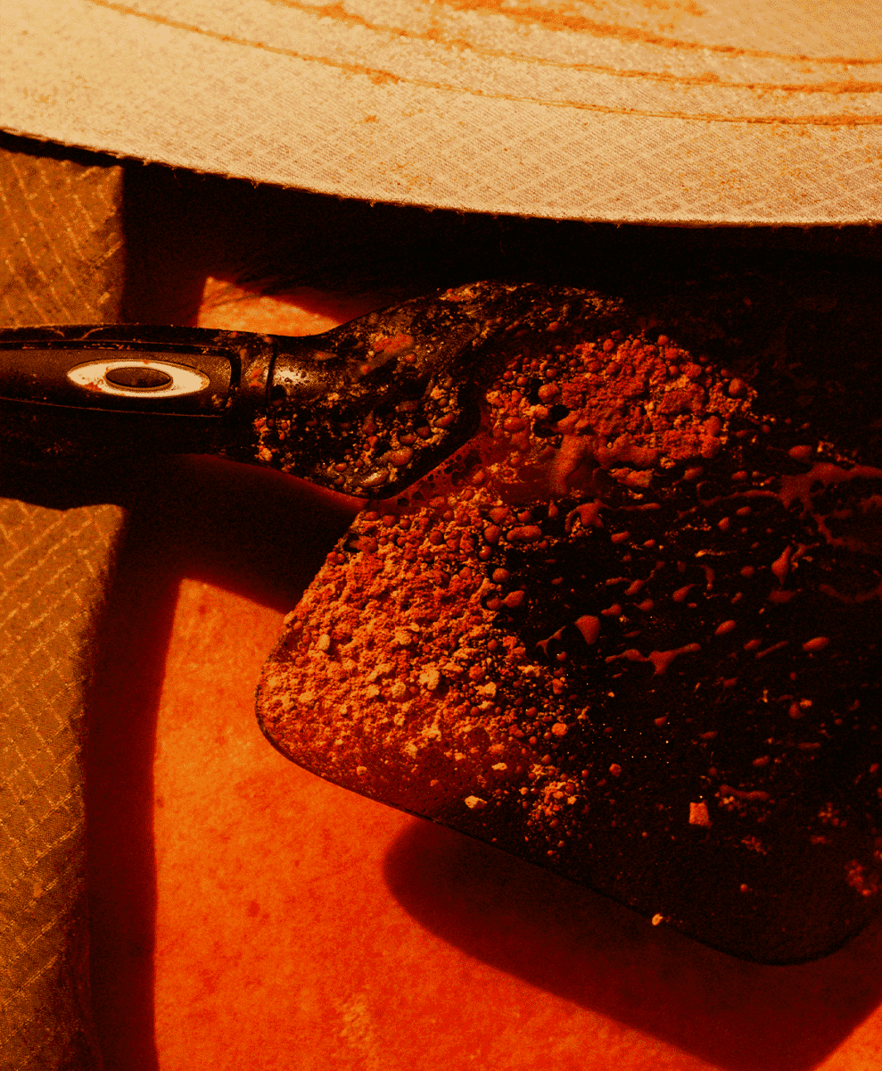 Macro shot of a black tool covered in reddish-brown powder.