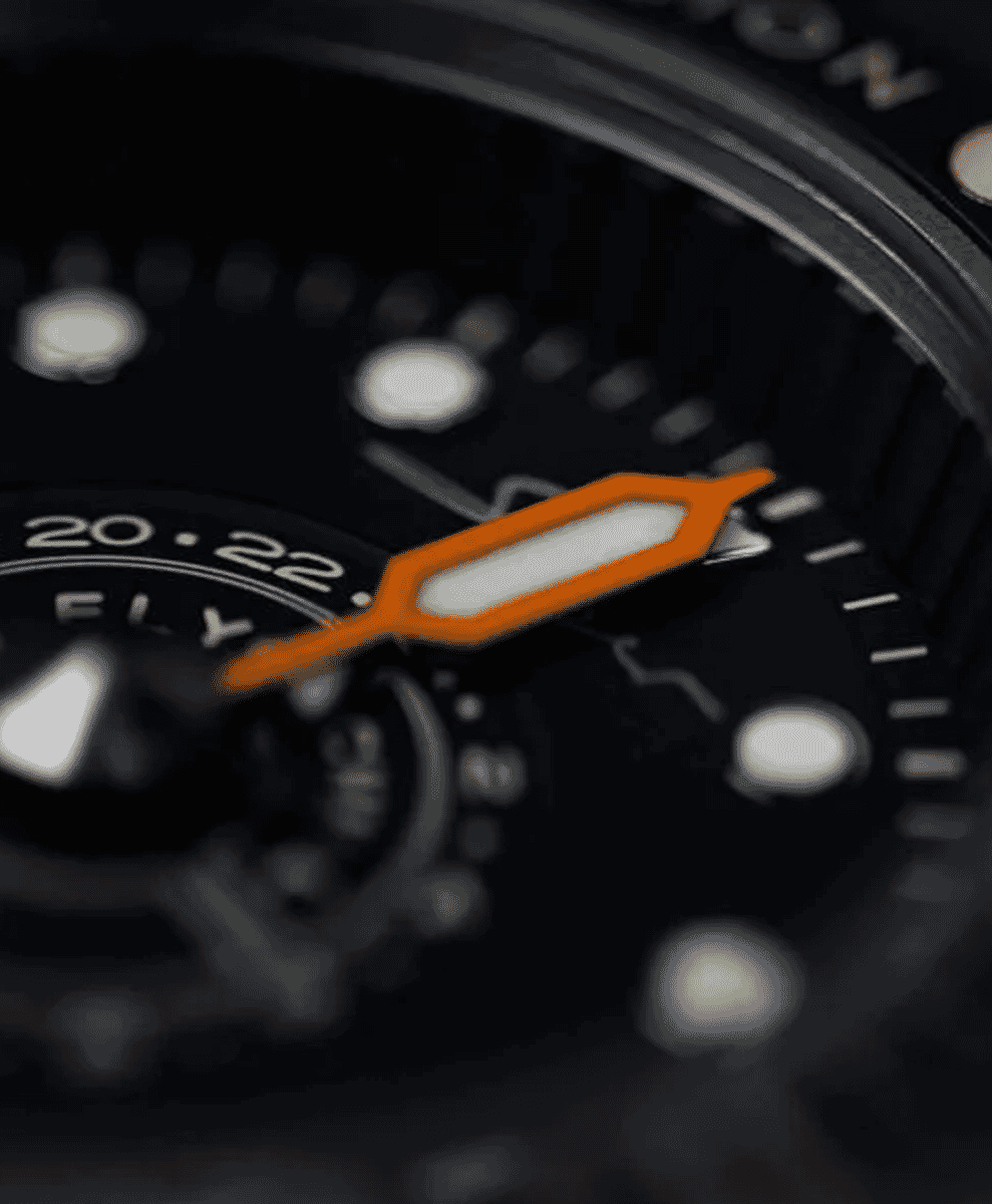 Close-up of a black wristwatch with an orange-tipped hand and luminous markers.