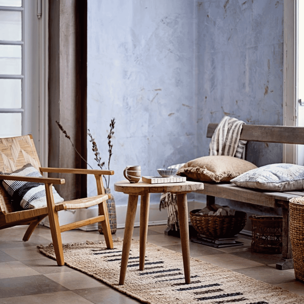 A rustic living room setup with a wicker chair and wooden bench.