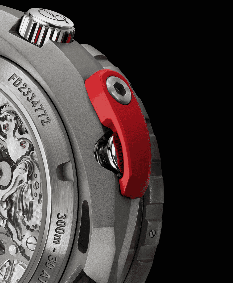 Close-up of a mechanical watch movement with visible gears and a distinctive red pusher against a black background.