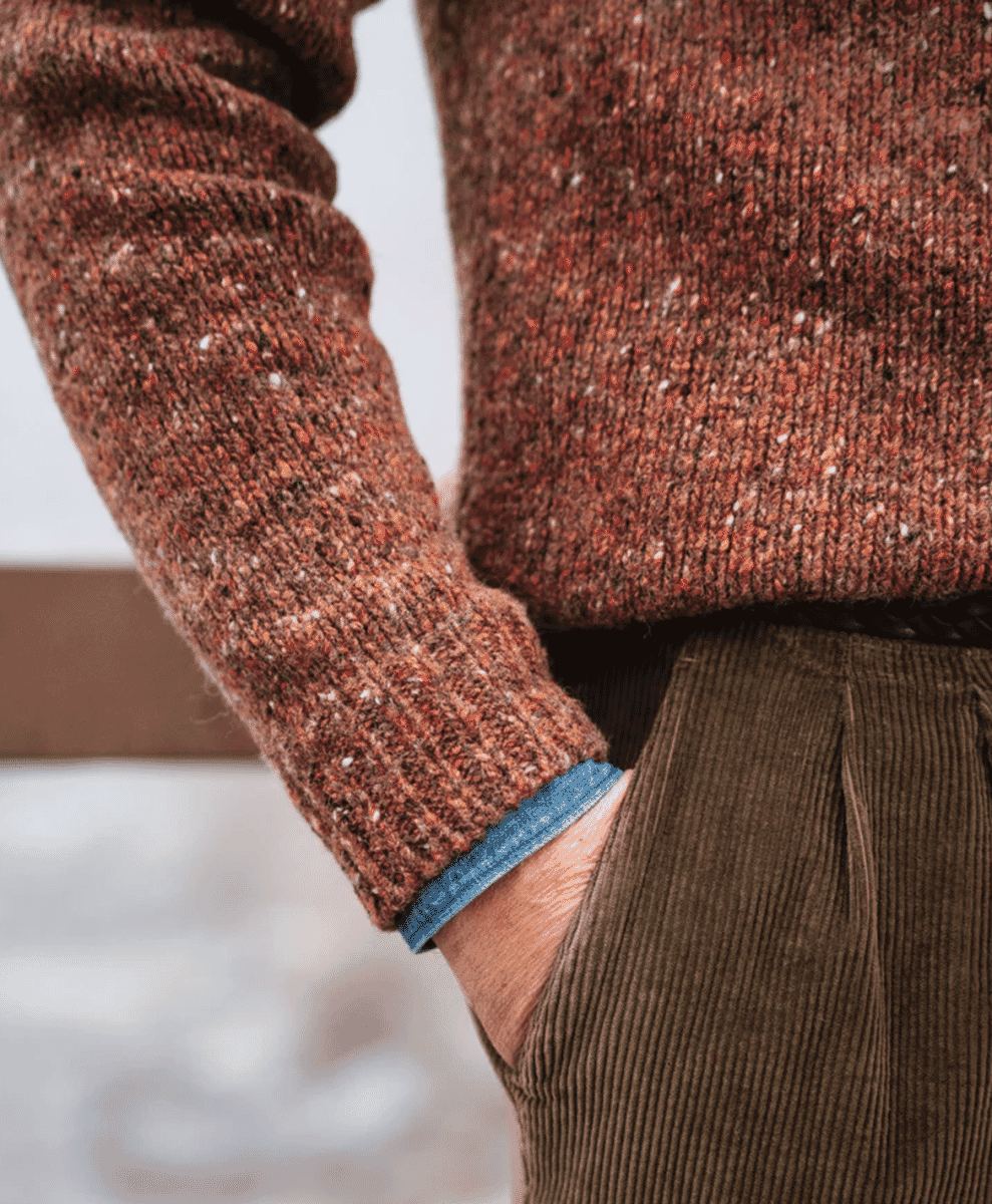 Close-up of a brown speckled knit sweater showing different colored flecks in the yarn.