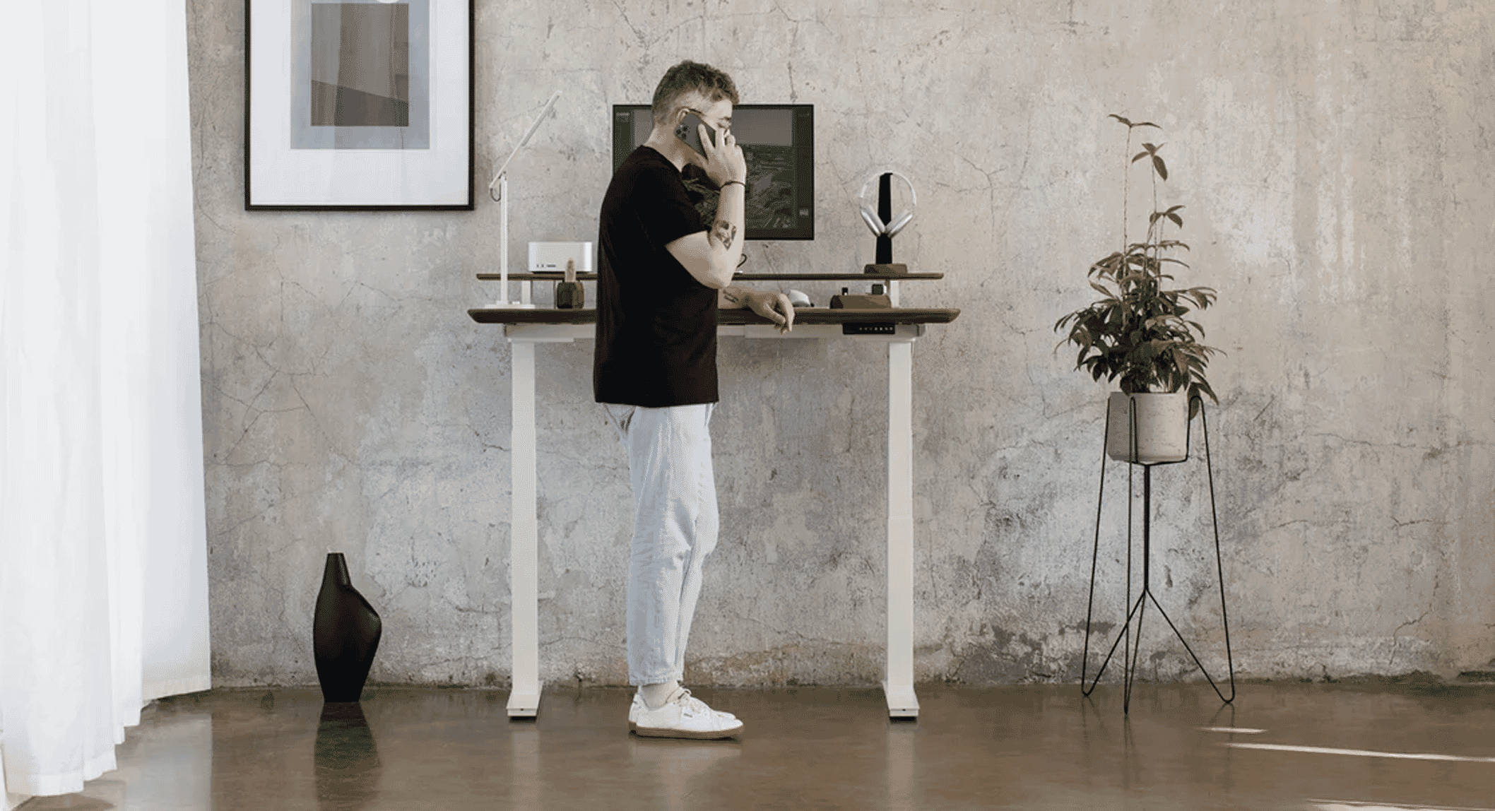 Man in casual attire working at a standing desk in a modern office with concrete walls.