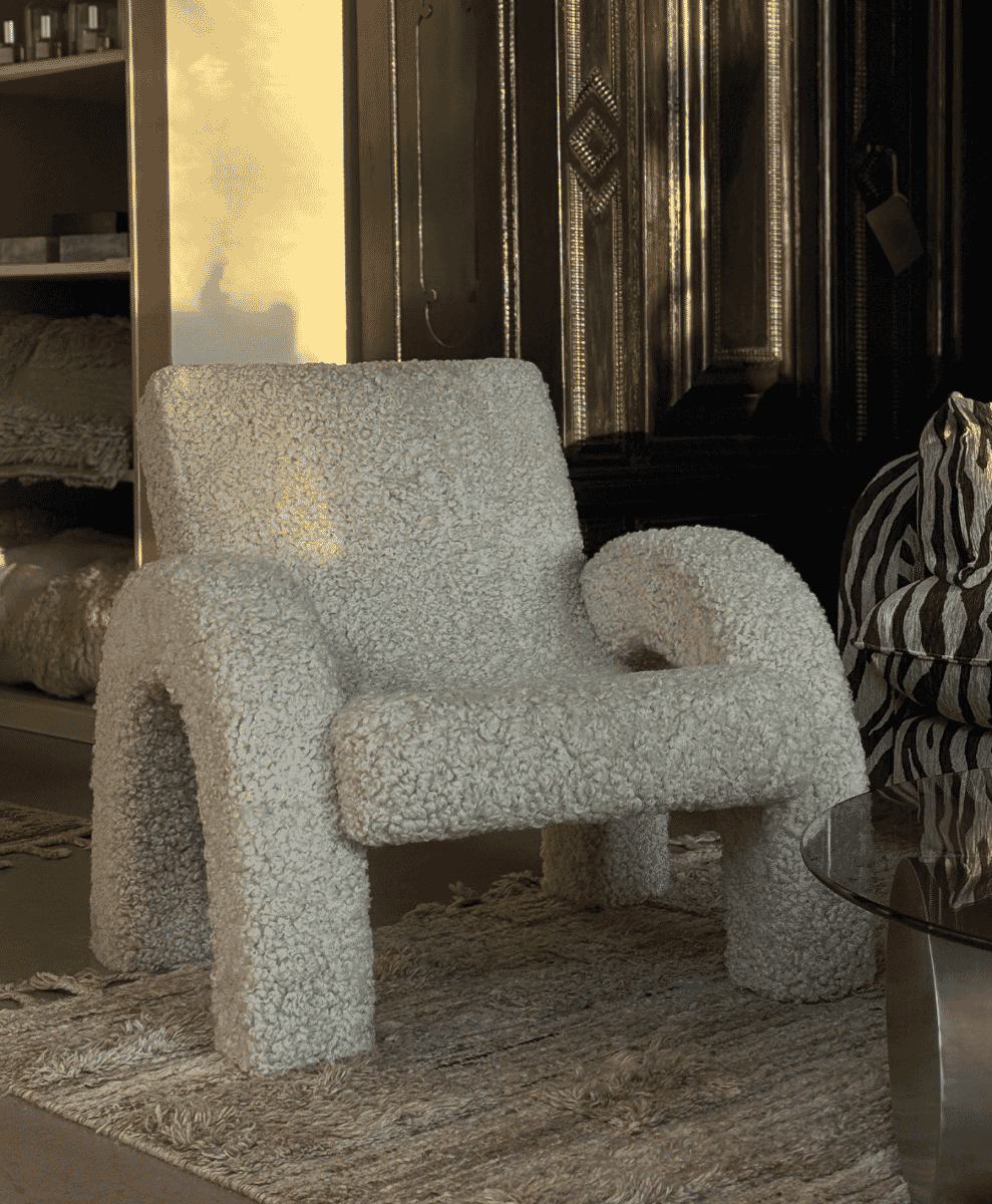 Plush off-white bouclé armchair in a luxury interior featuring zebra-print accents and wooden paneling.