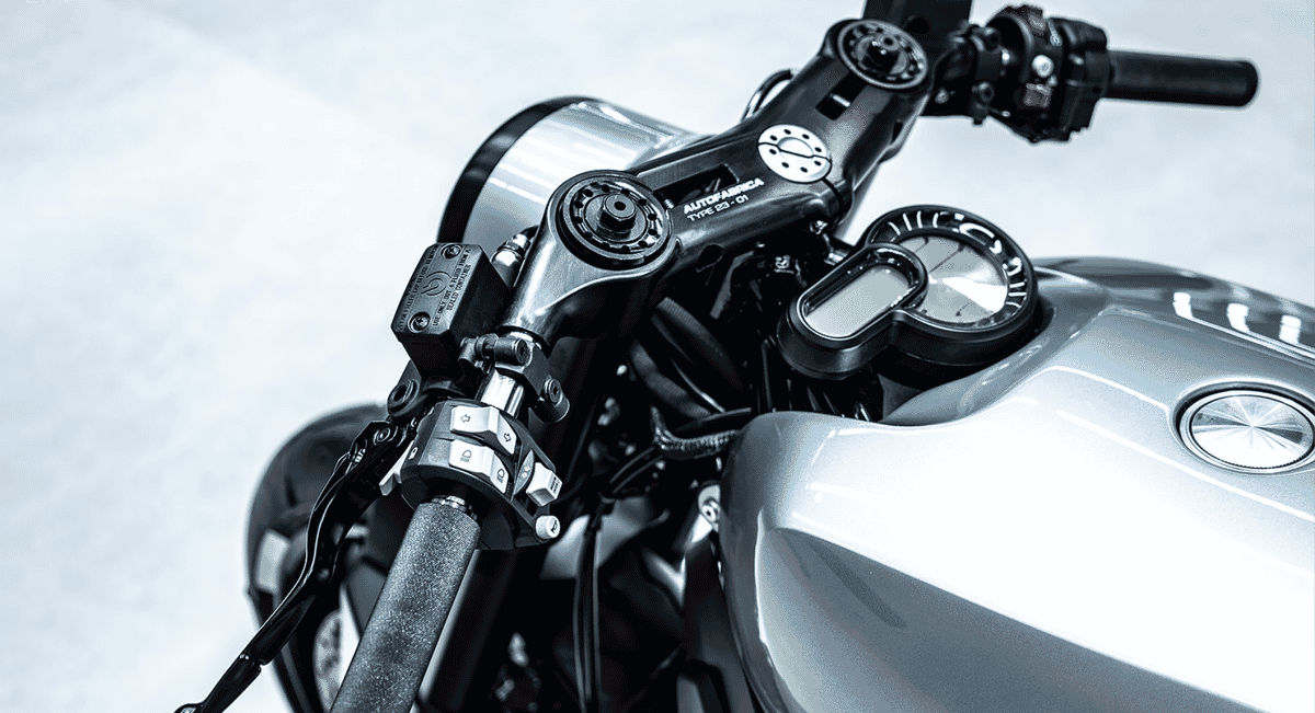 Macro view of the motorcycle handlebars and metallic fuel tank top featuring a clean, minimalist interface.