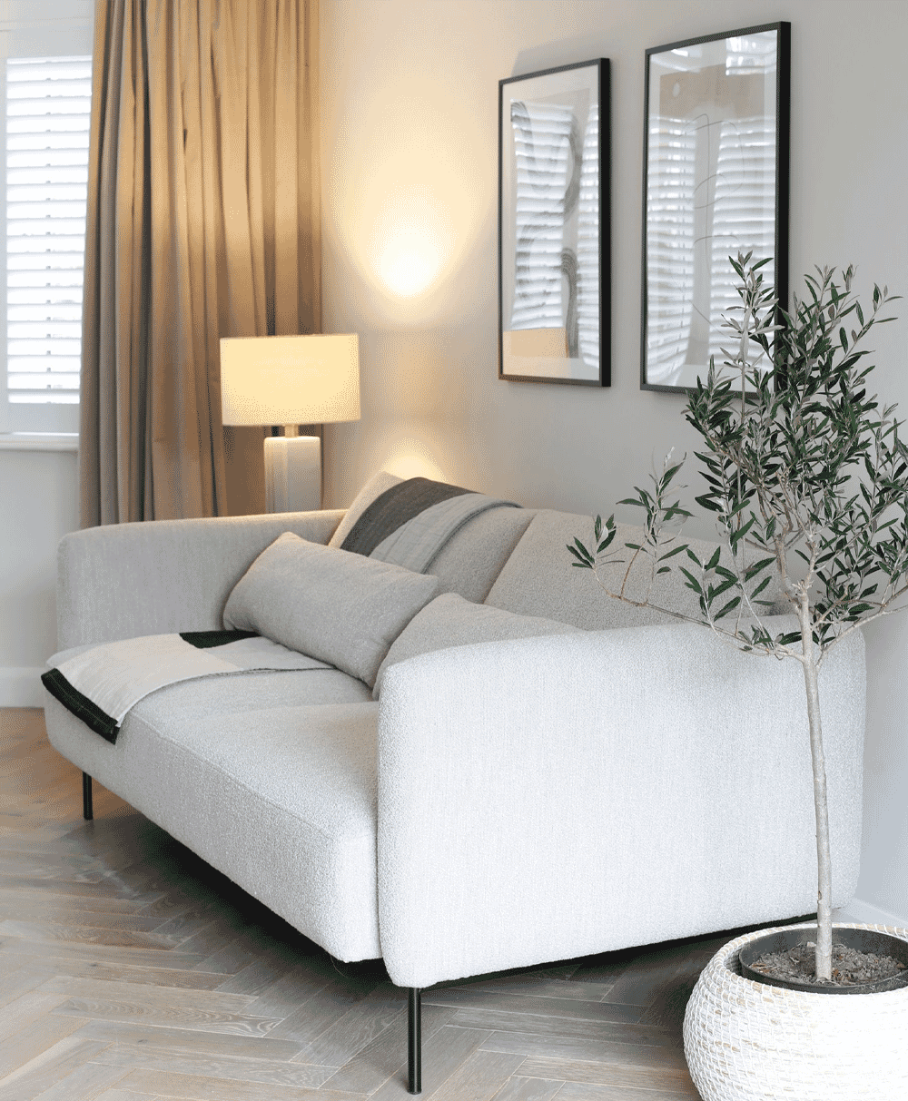 White textured sofa with a potted olive tree and warm ambient lighting in a modern room.
