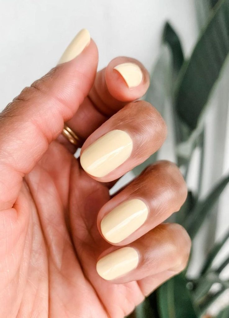 Pale butter yellow manicure on short oval nails.