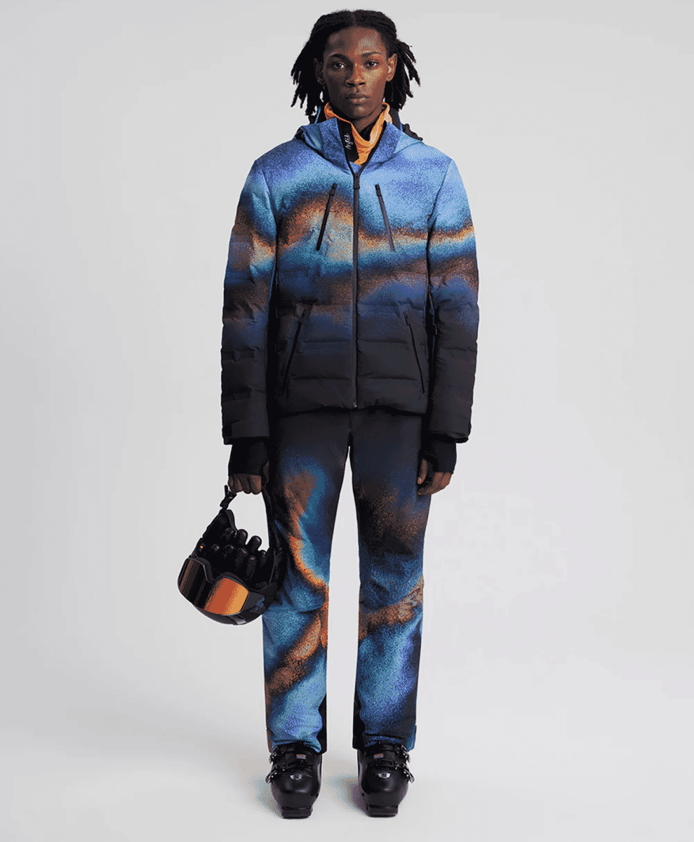A model wearing a vibrant blue and orange gradient ski jacket and matching pants.