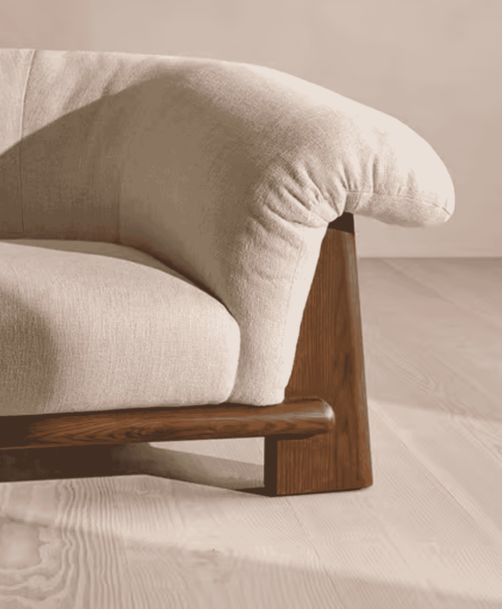 Close-up of a modern sofa with textured beige fabric and light wood legs.