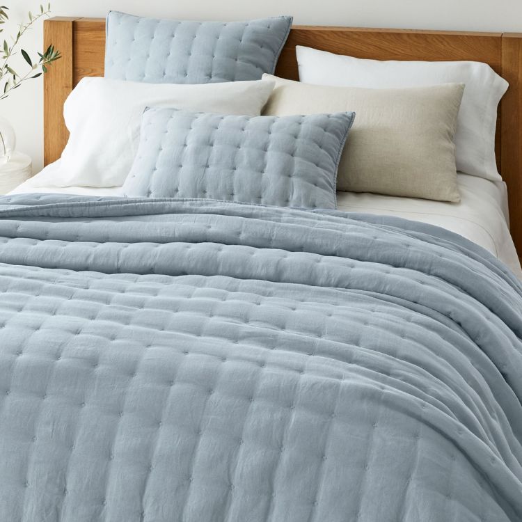 A light-colored flax linen quilt and matching shams.