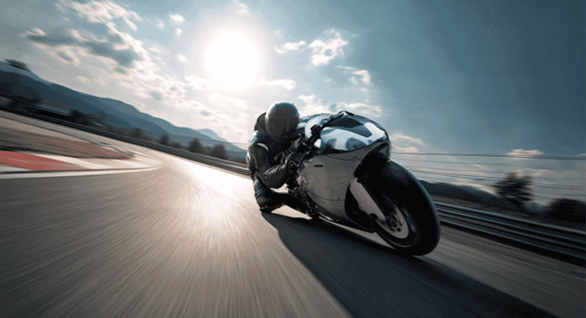 Motorcyclist in black racing leathers leaning deep into a turn on a sunlit racetrack.