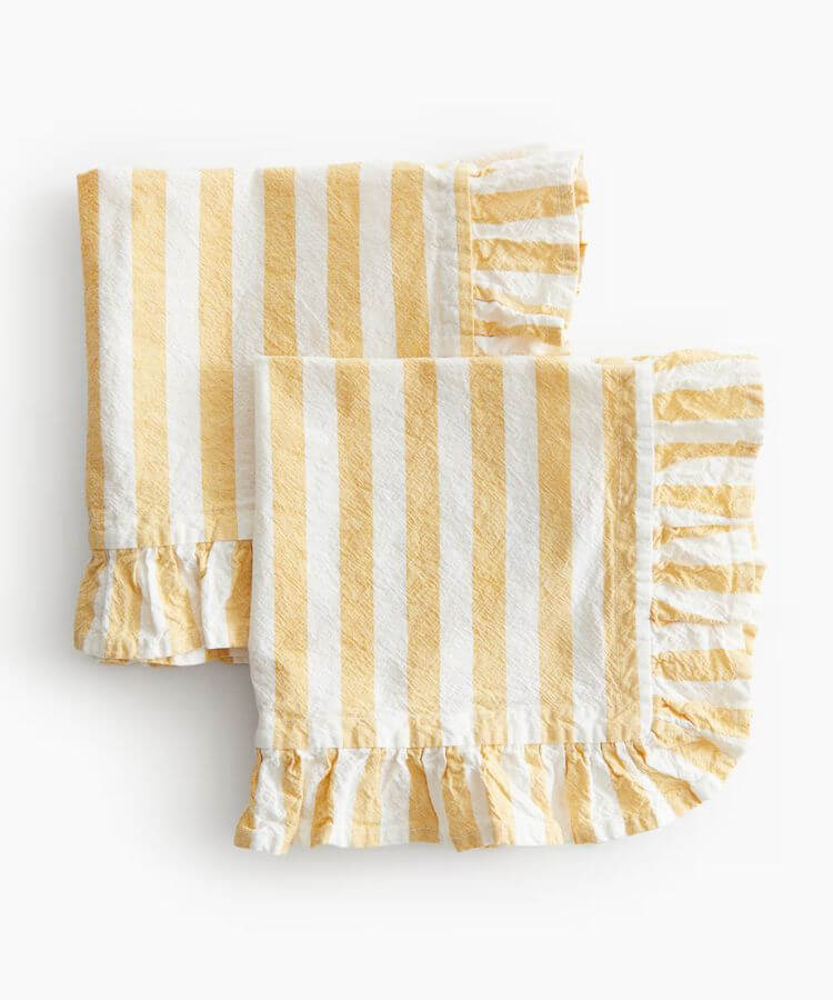 Pair of yellow napkins with white ruffle trim.
