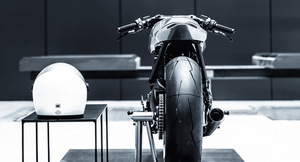 A minimalist studio shot of the Type 23 motorcycle next to a matching bespoke Hedon helmet on a stand.