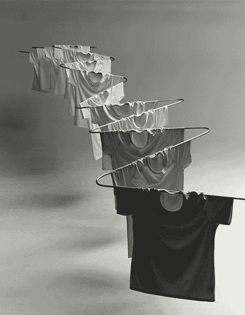 Artistic monochrome arrangement of T-shirts in varying shades on a rack.