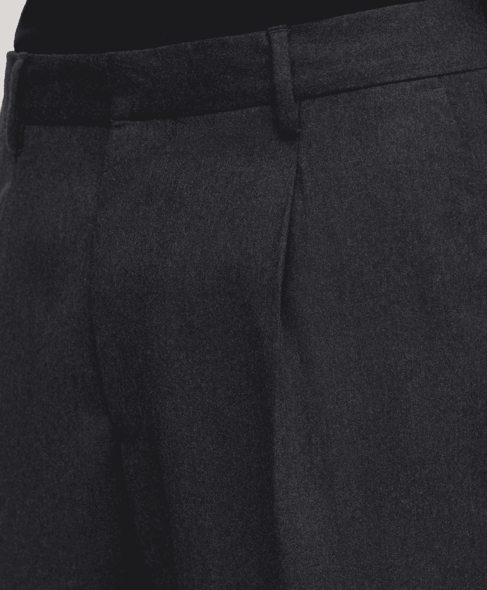 Close-up detail of the tailored waistband and pleats on dark gray wool trousers.