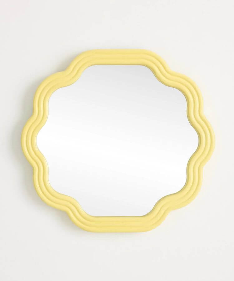 Wall mirror with a decorative scalloped wooden frame in yellow.