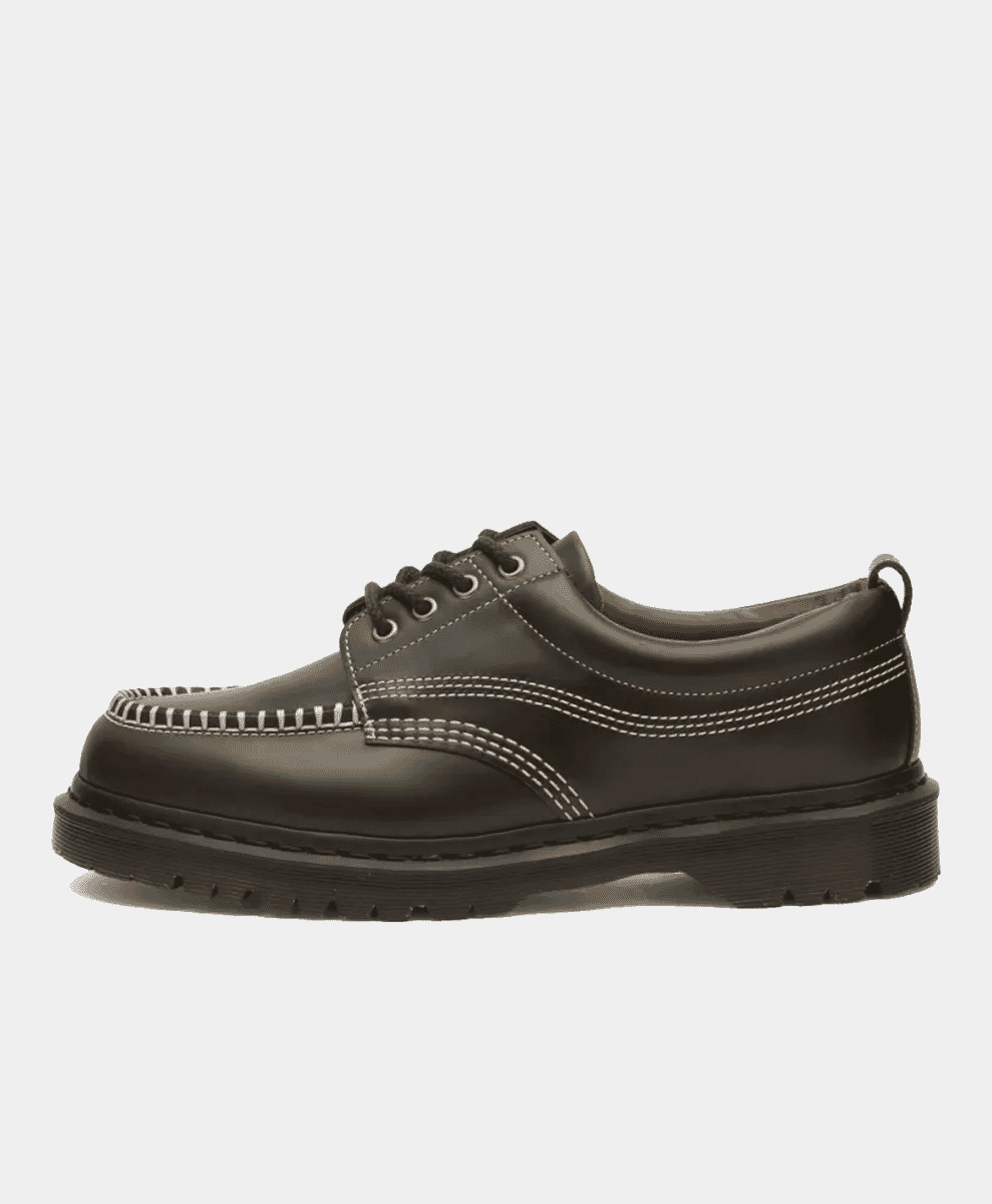 A side profile of a black leather Dr. Martens Lowell shoe with white stitching.
