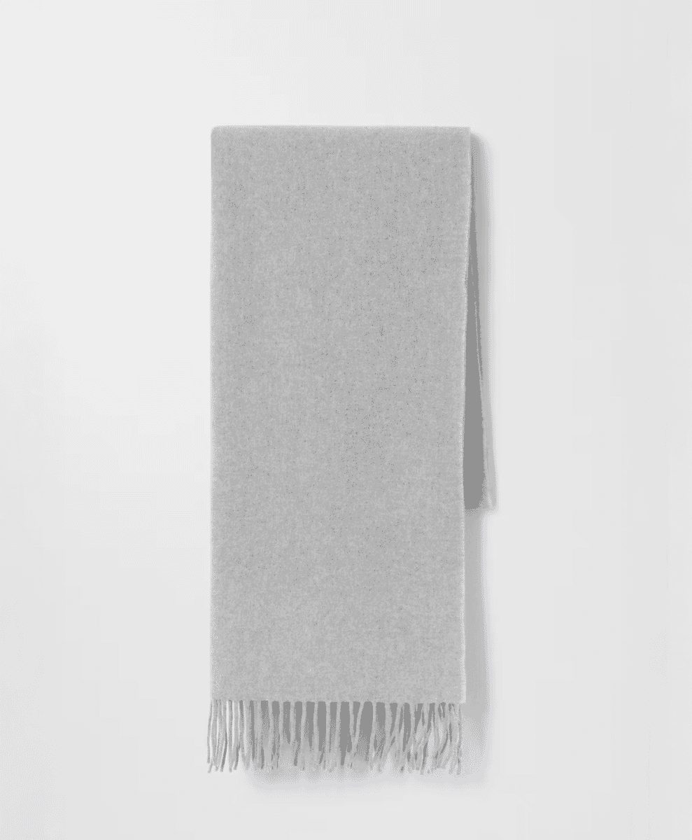A light gray oversized cashmere wool scarf with fringed edges.