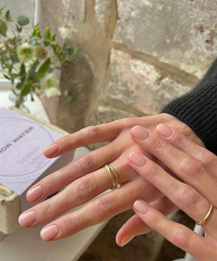 Sleek and polished neutral beige manicure on a minimalist background.