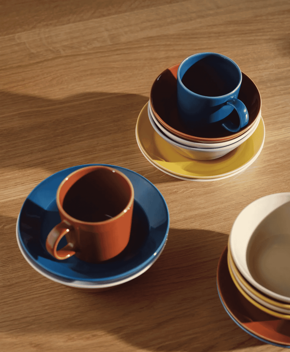 A collection of colorful Iittala Teema ceramic mugs arranged on a wooden table.