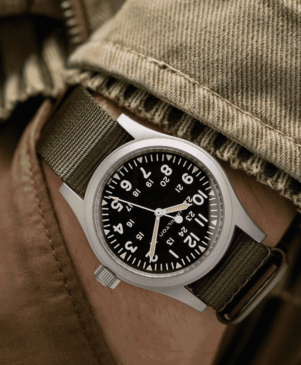 A person wearing a Hamilton Khaki watch with a beige denim jacket.