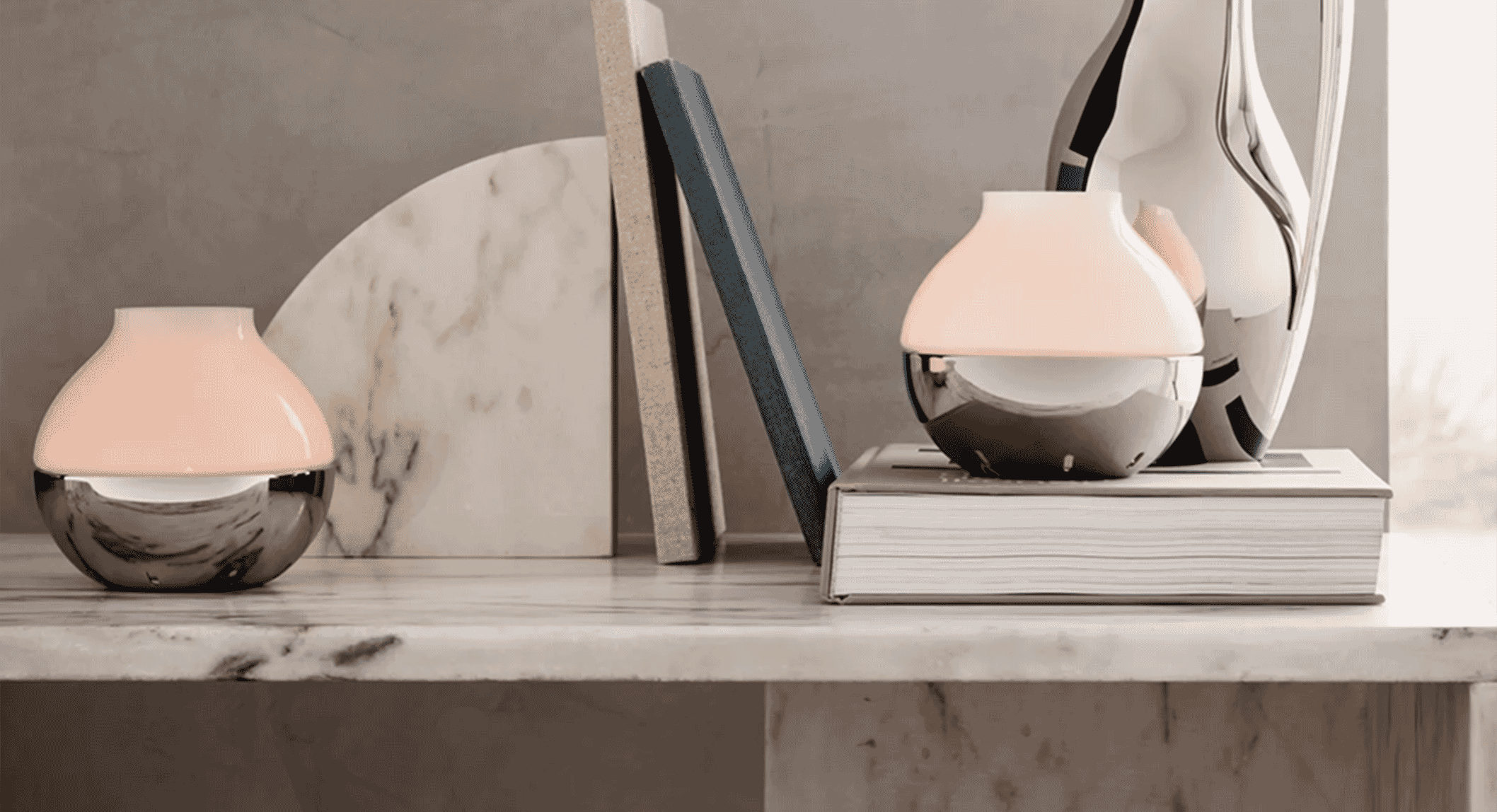 A minimalist shelf display featuring marble bookends and sleek ceramic vases.