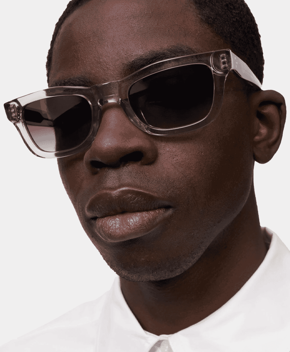 Close-up portrait of a man wearing transparent rectangular frame sunglasses.